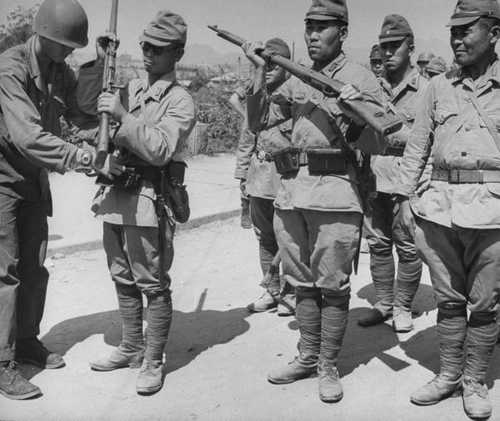 Japanese soldiers surrender their weapons
