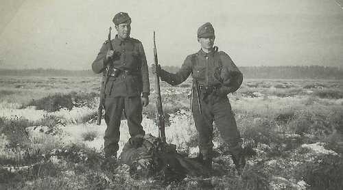 Finnish soldiers pose with dead Soviet soldier
