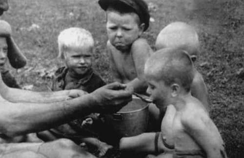 A German Soldier feeds a group of Russian Children